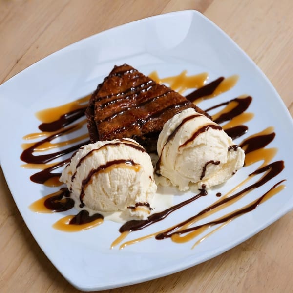 Brownie with two scoops of vanilla ice cream, drizzled with chocolate and caramel sauce.